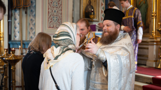 Isä Lassi Nuutinen siunaa ristillä kirkossa 2025 