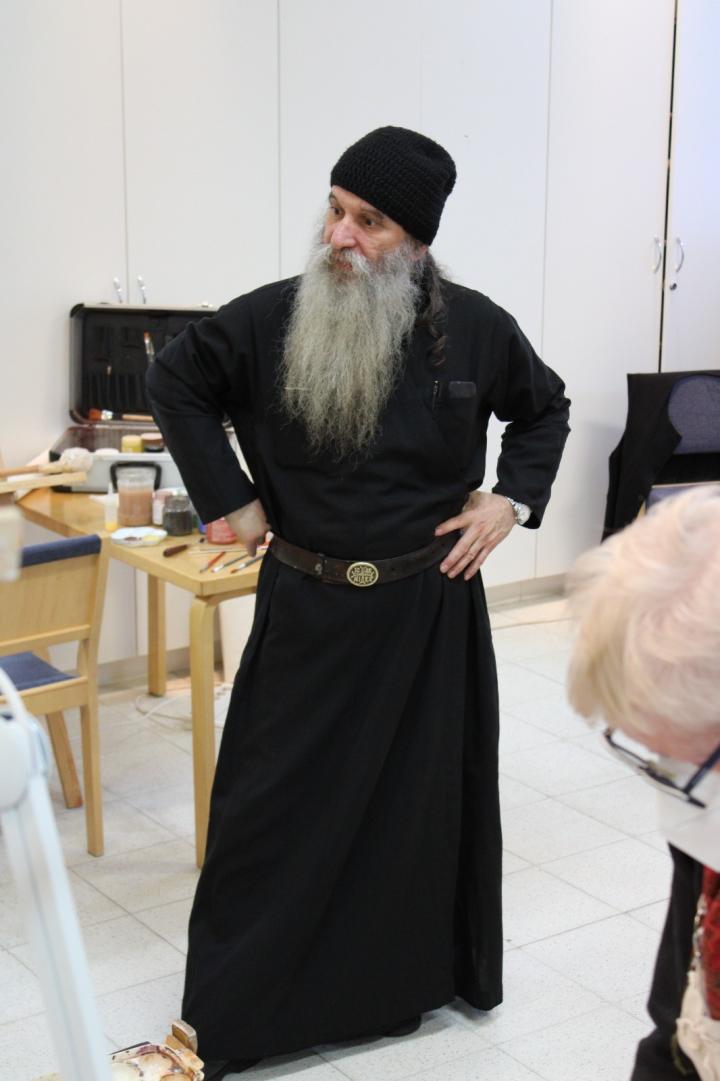 Mustaan viittaan pukeutunut ortodoksipappismunkki isä Luukas opettaa ikonimaalausta Valamon opiston luokassa