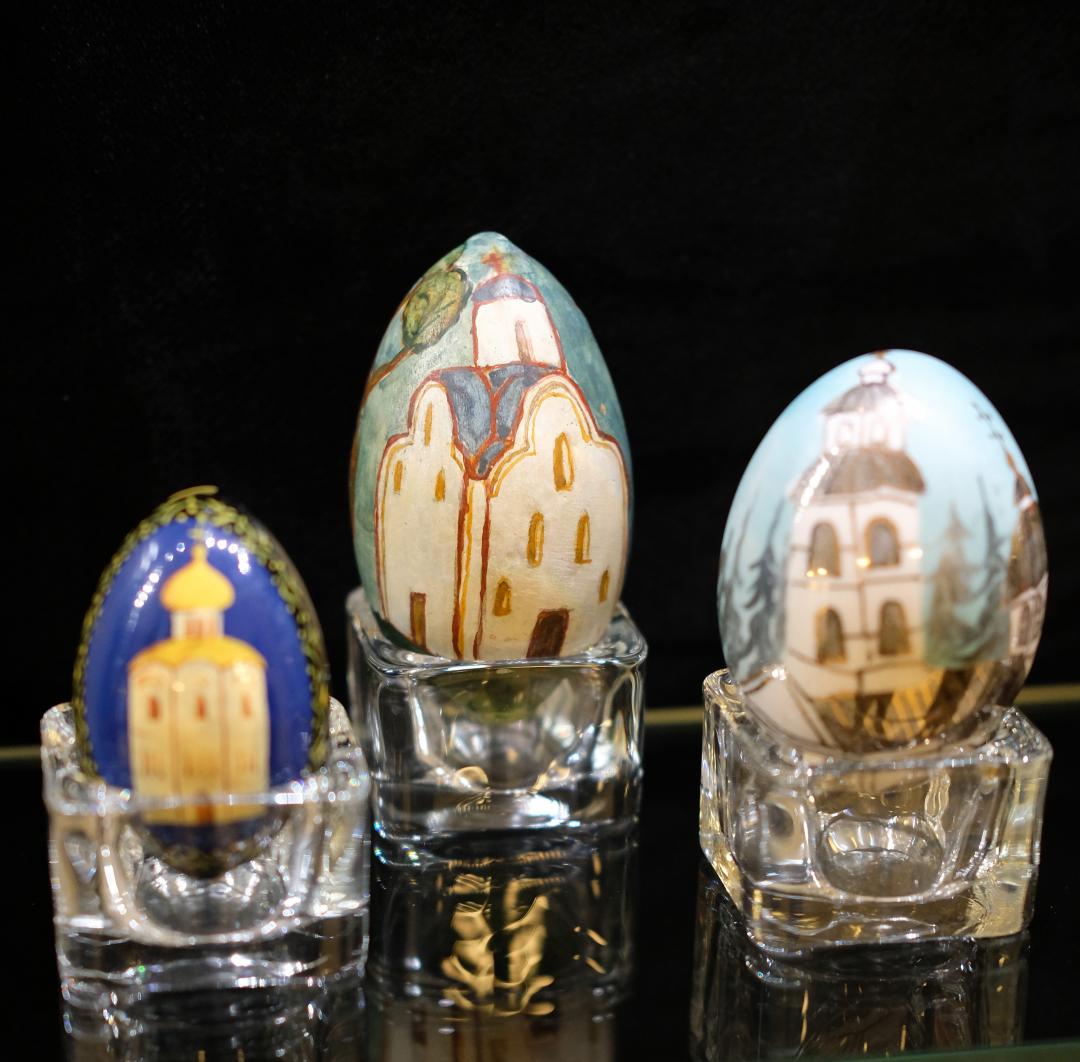 Rivissä tasolla kolme lasista pääsiäismunaa joihin on kuvattu pyhäkköjä
