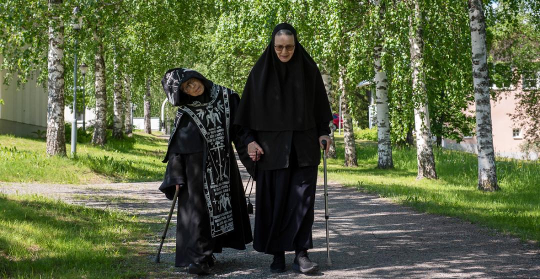 Skeemanunna Melania ja nunna Johanna kävelevät Lintulan luostarin kesäistä koivukujaa pitkin