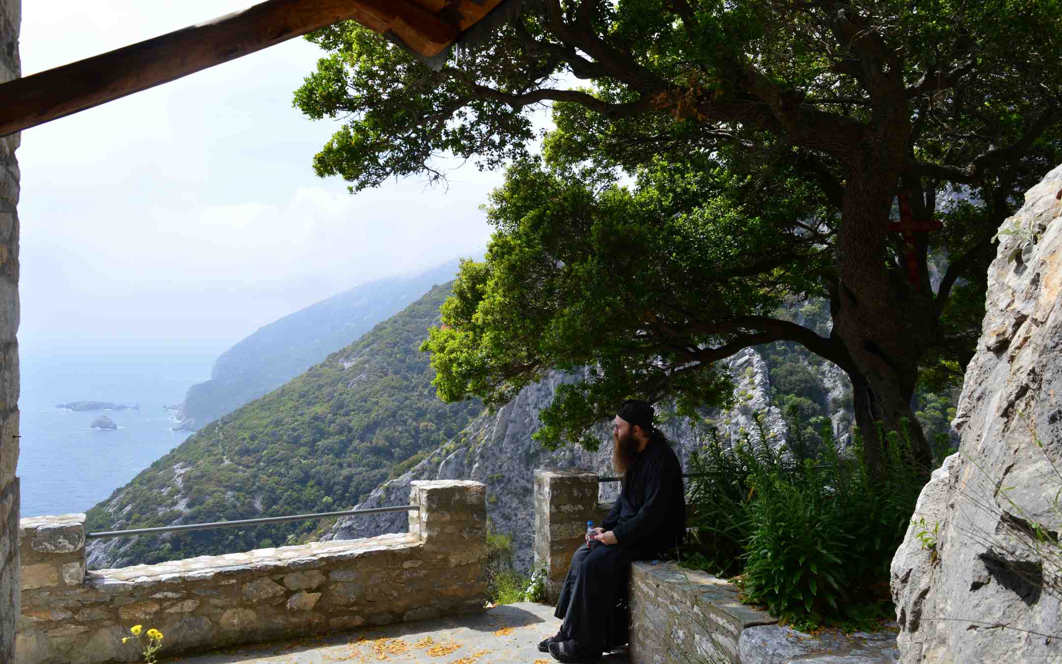 Pappismunkki Damaskinos Ksenofontoslainen istuu levähtämässä näköalatasanteella vuorenrinteellä Athos-vuorella Kreikassa