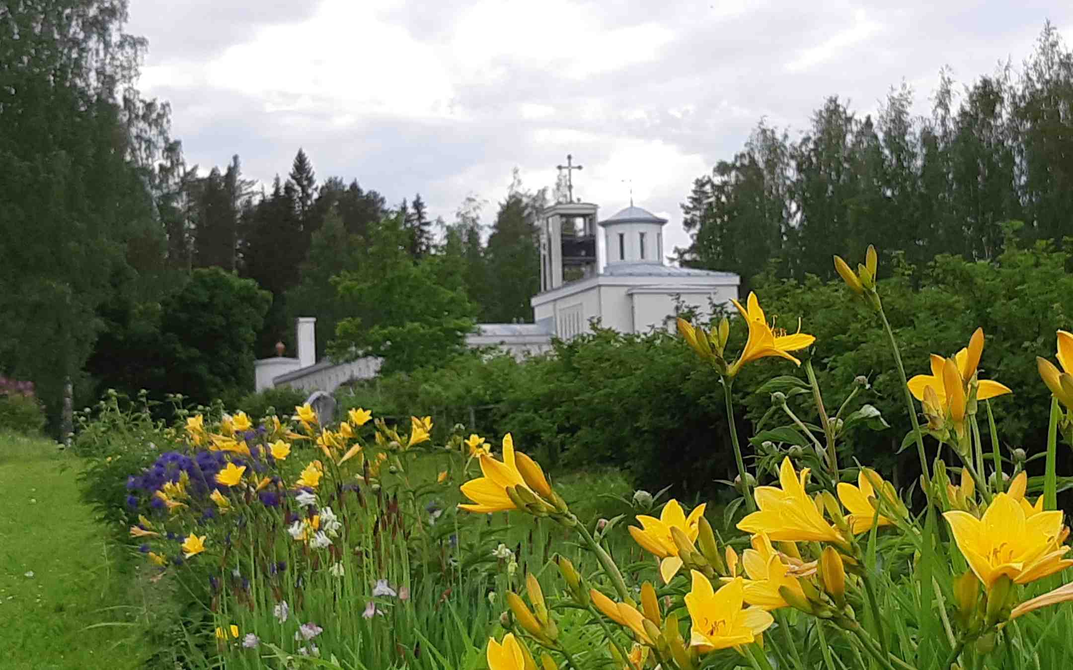 Lintulan luostari kuvattuna kesäpäivänä kukkapenkki etualalla