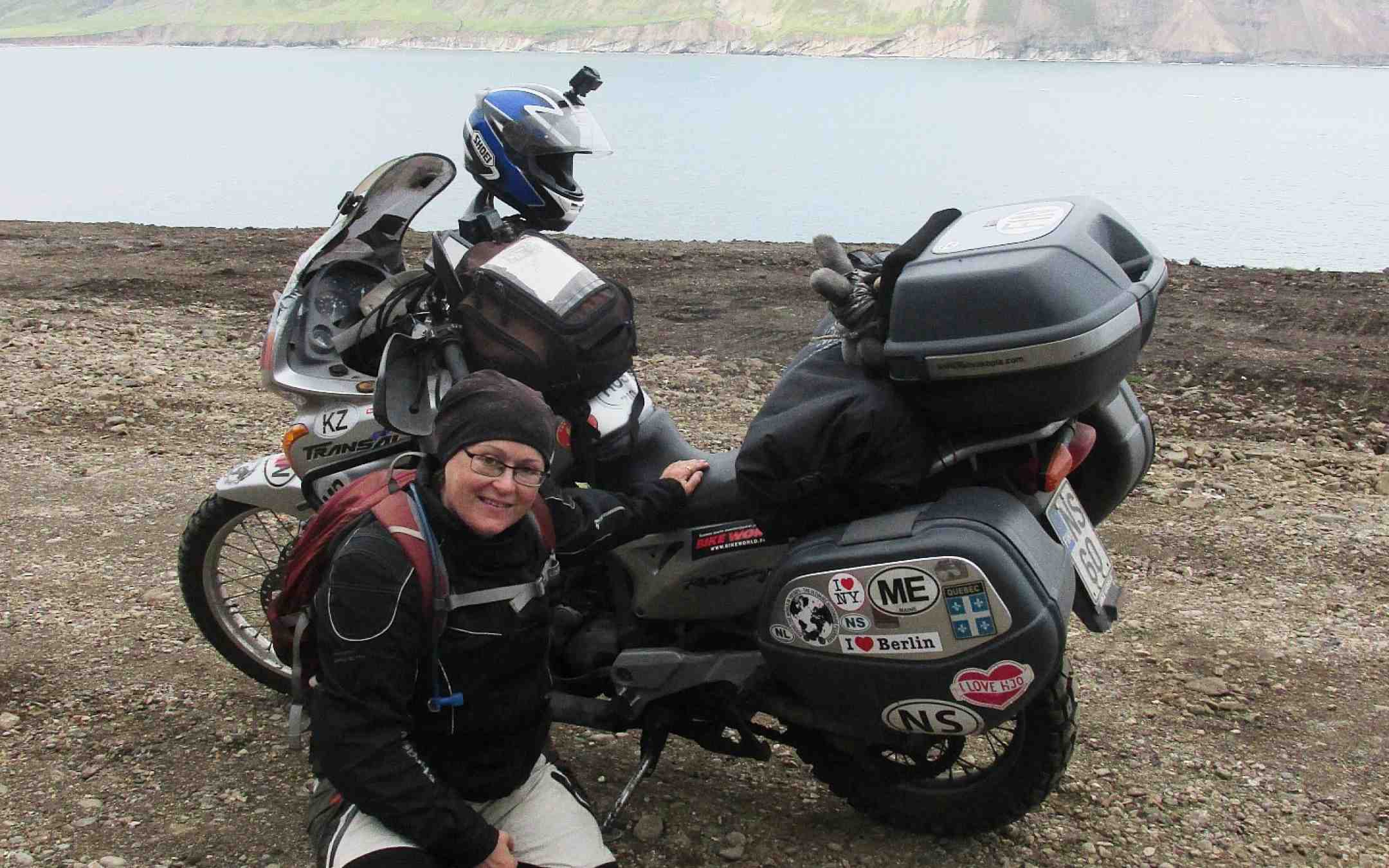 Kanttori Minna Jokinen poseeraa moottoripyöränsä vierellä Islannissa vuoret taustallaan