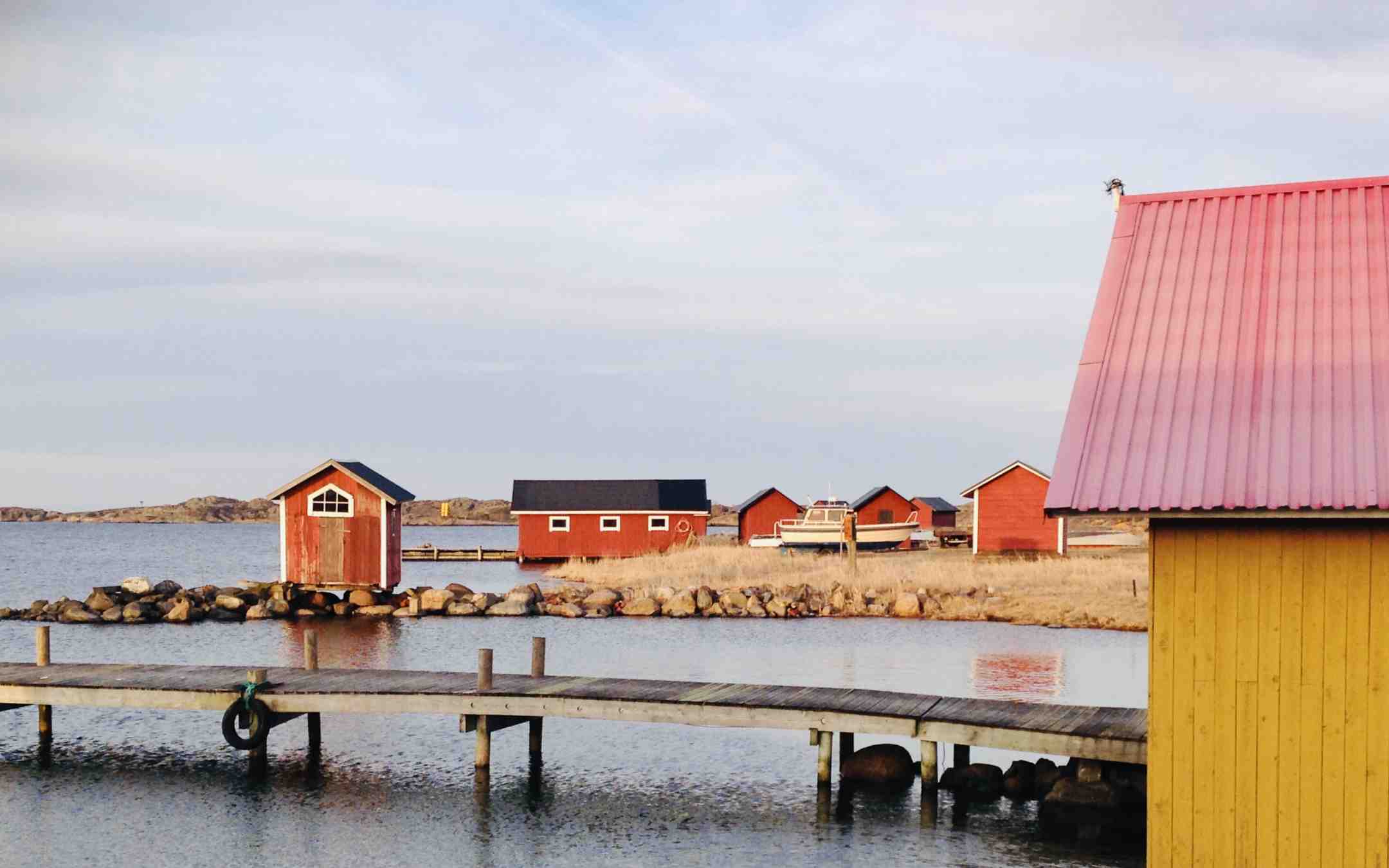 Laituri ja pieniä värikkäitä rakennuksia Utön saarella meren rannassa pilvisenä kesäpäivänä
