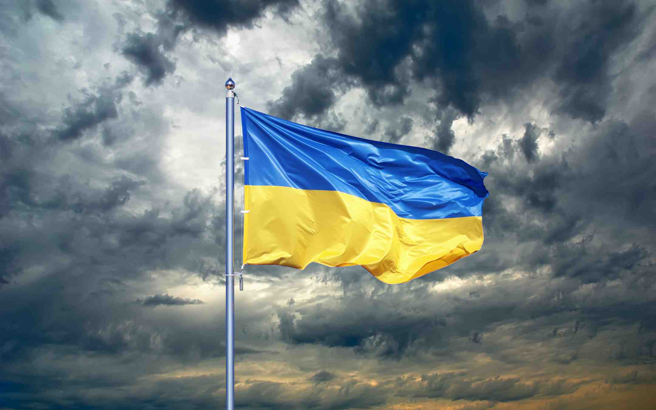 Ukrainan sinikeltainen lippu liehuu tuulessa taustallaan synkkiä myrskypilviä