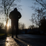 Yksinäinen mies kävelee aamuauringossa