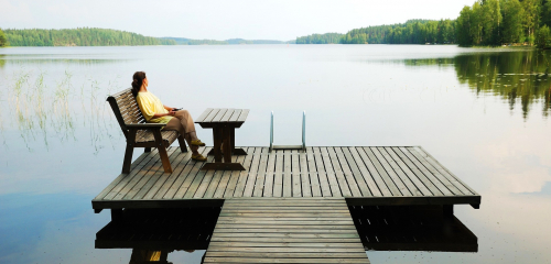 Laiturilla istuva nainen ja järvi