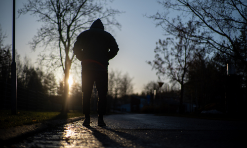 Yksinäinen mies kävelee aamuauringossa