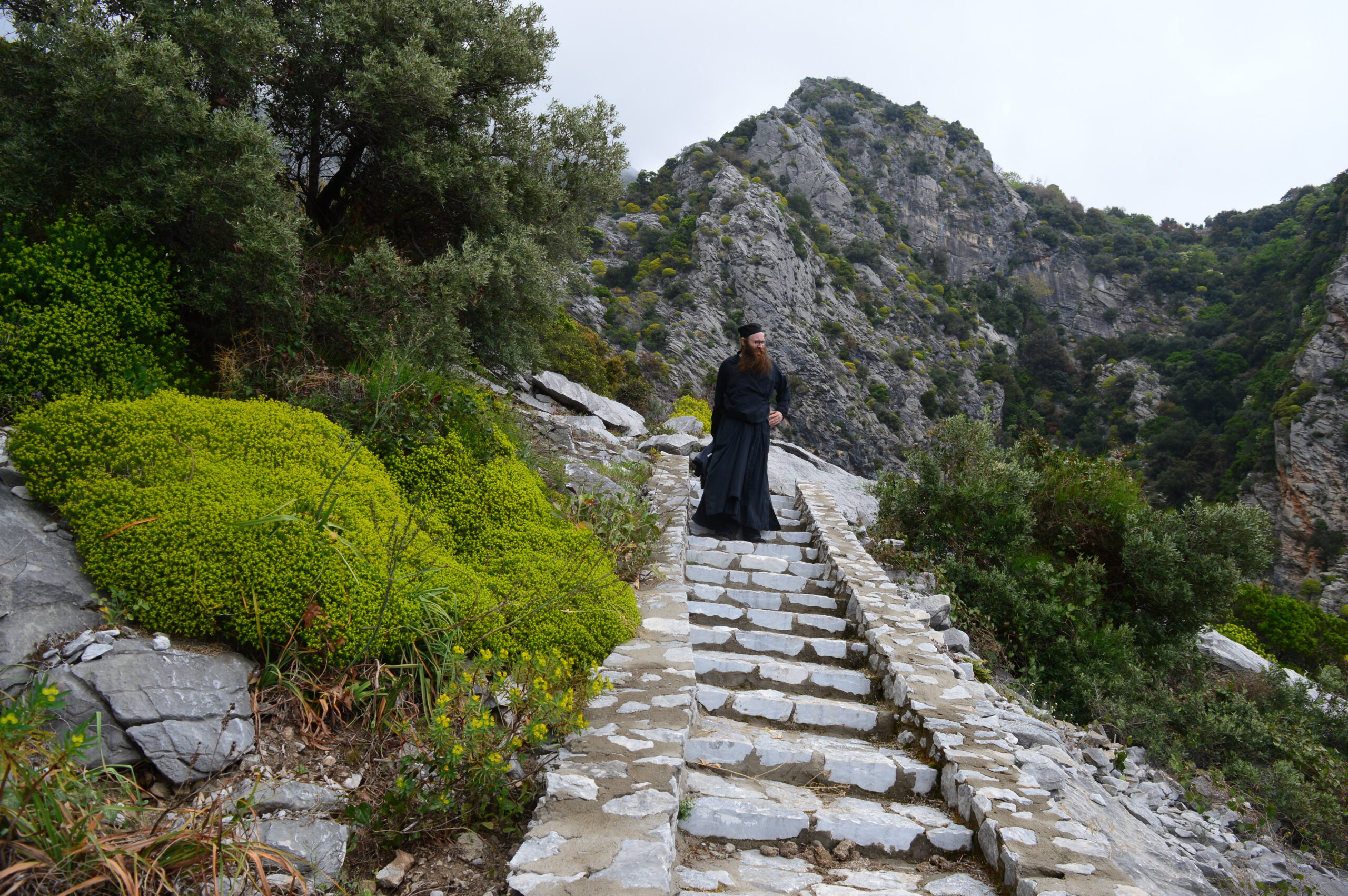 Pappismunkki Damaskinos Ksenofontoslainen laskeutuu kivisiä rappusia pitkin alas vuorenrinnettä Athos-vuorella Kreikassa