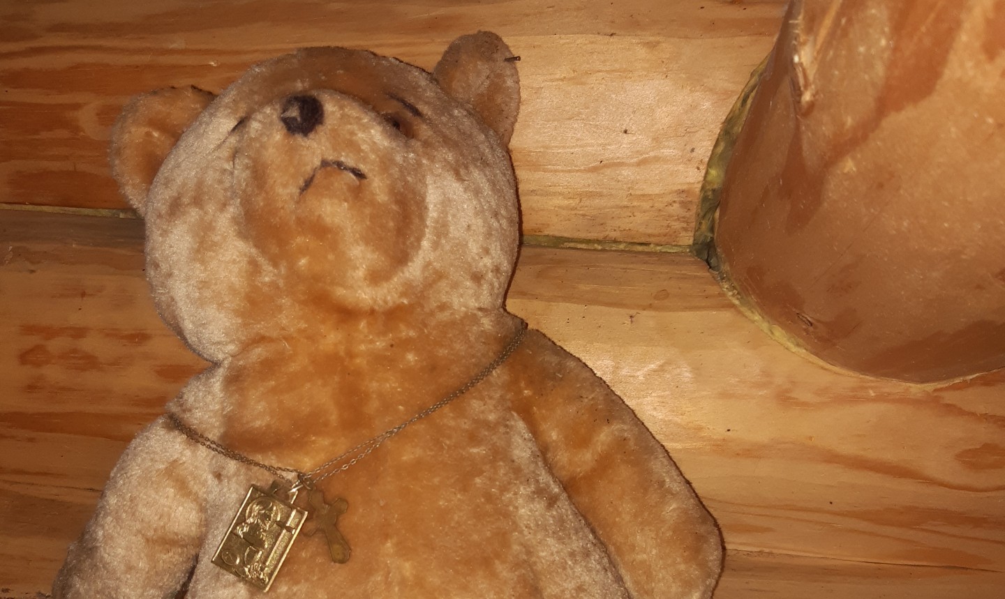 Uppo-nalle kuvattuna puunväristä hirsiseinää vasten