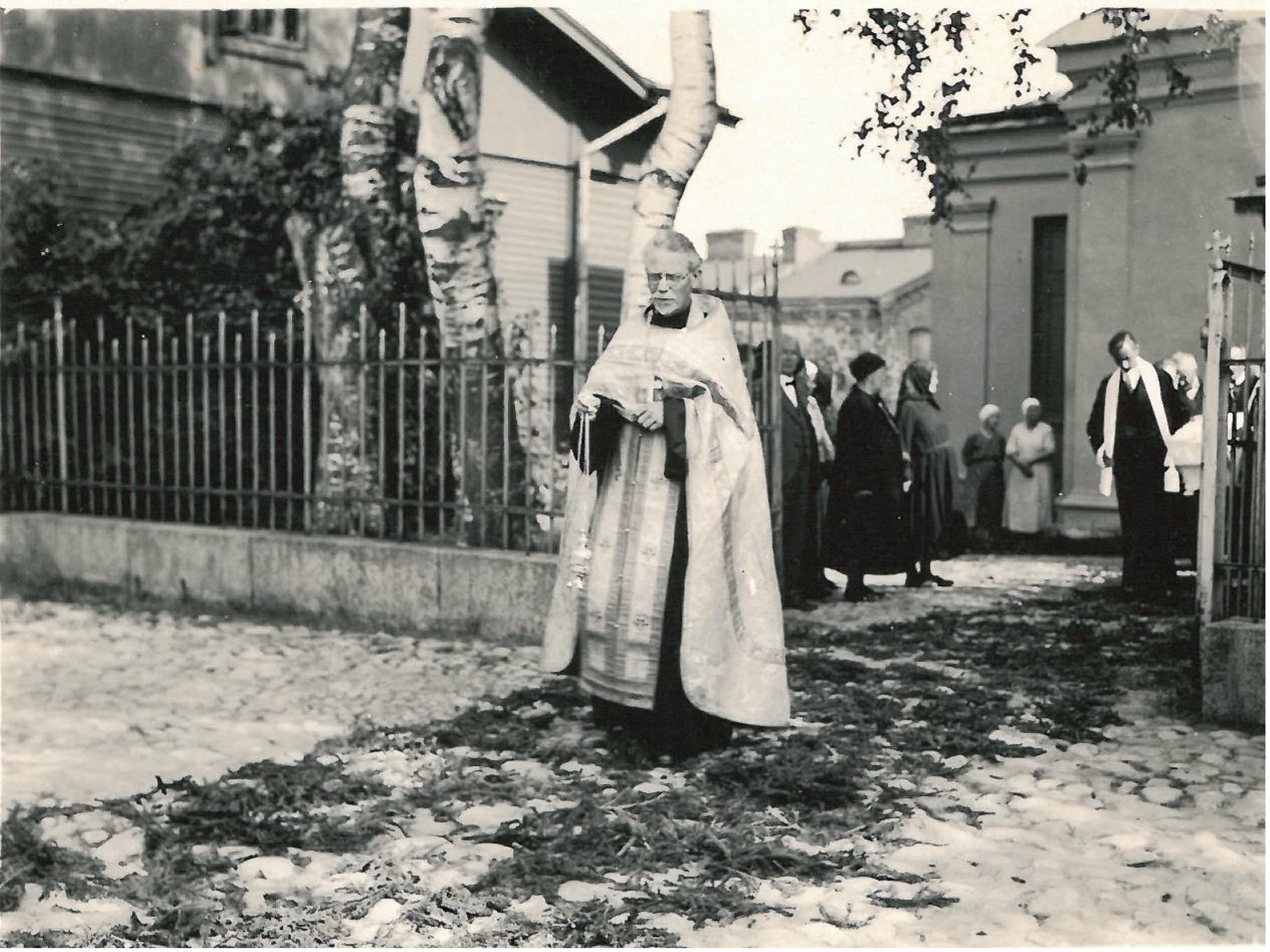 Rovasti Arsenij Razumov linnoituksen kirkon edessä vanhassa mustavalkoisessa valokuvassa