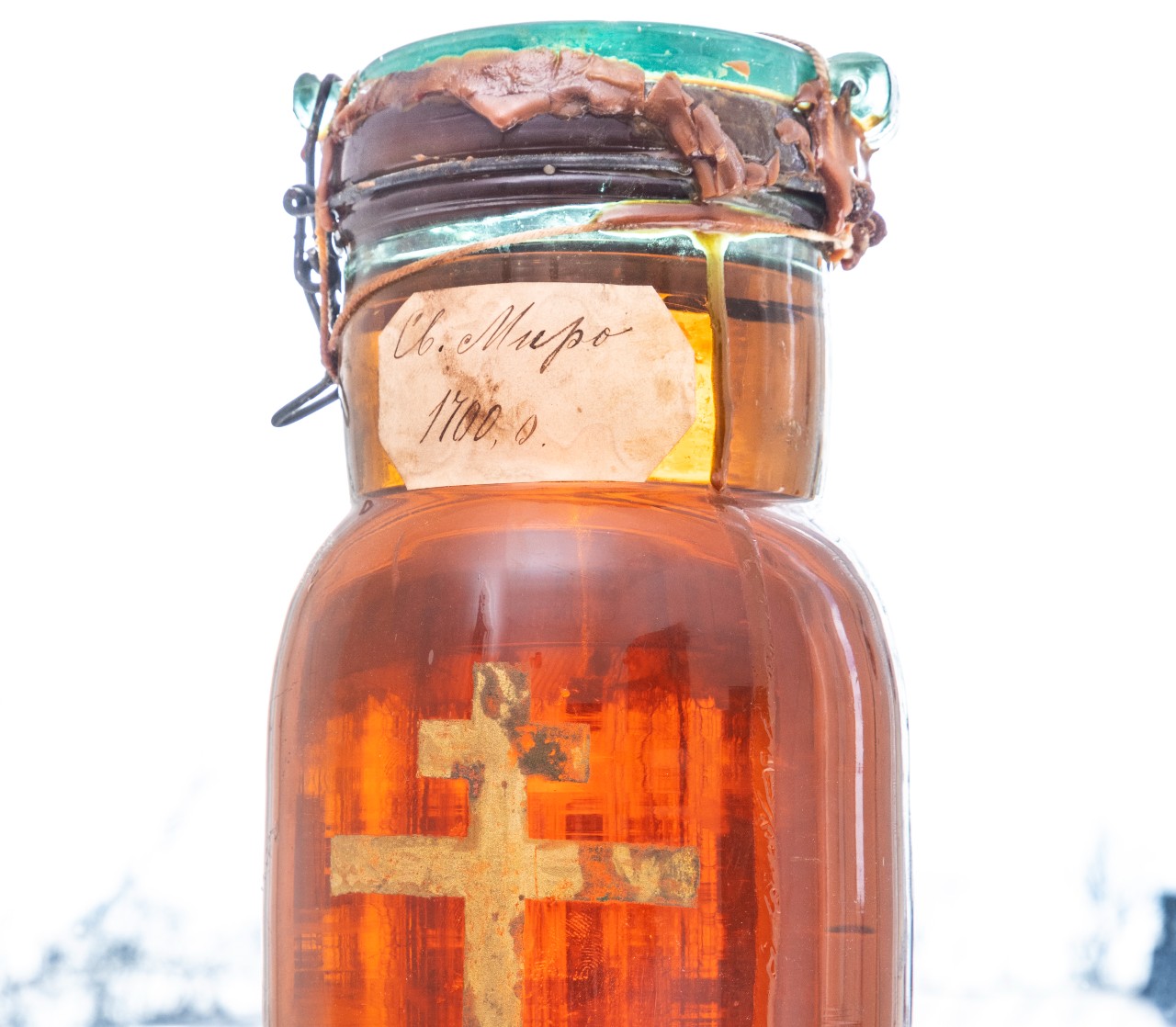 Pyhää meripihkan väristä mirhaa kultaiselle ristillä koristetussa lasiastiassa