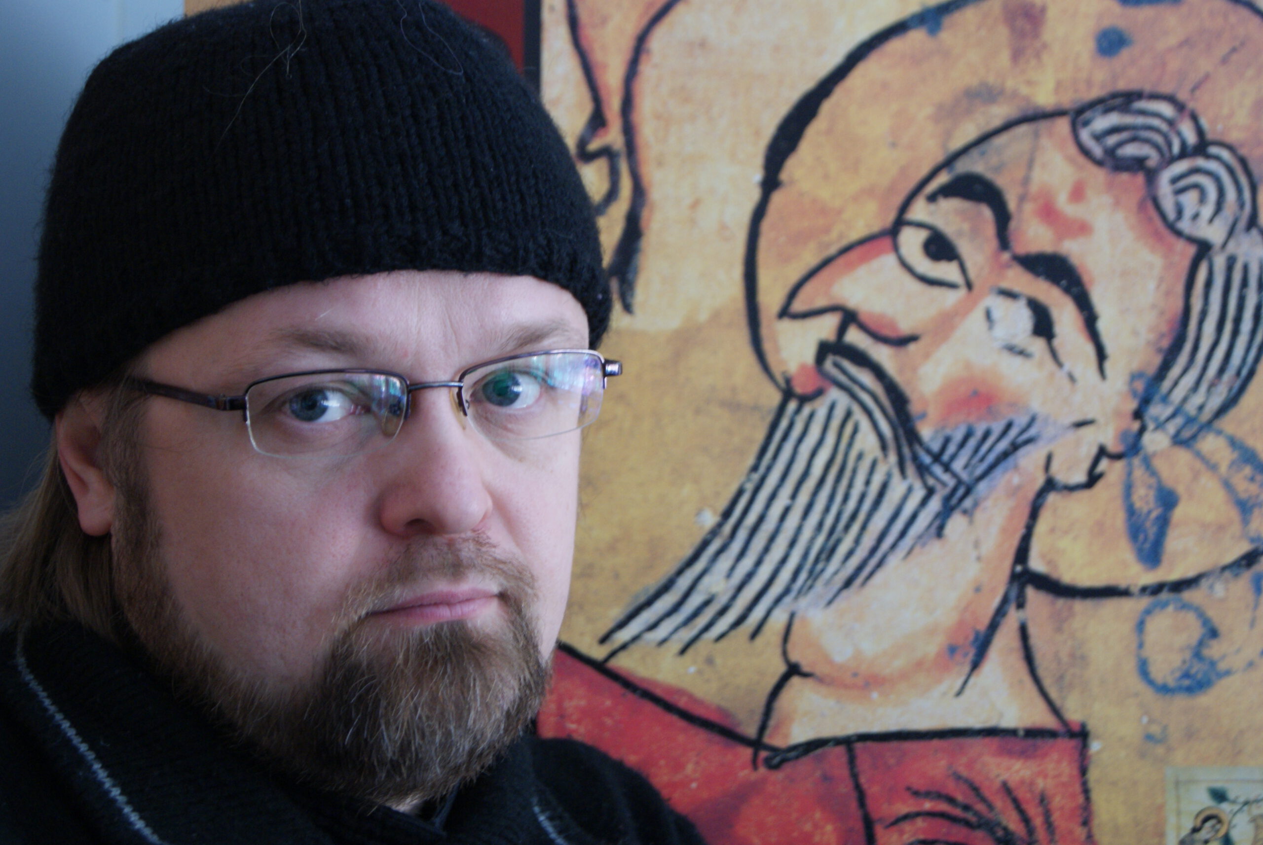 Pappismunkki Serafim Seppälä kuvattuna miestä esittävä maalaus taustallaan