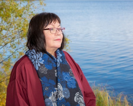 Kirjailija Raili K. Miettinen seisoo järven rannalla