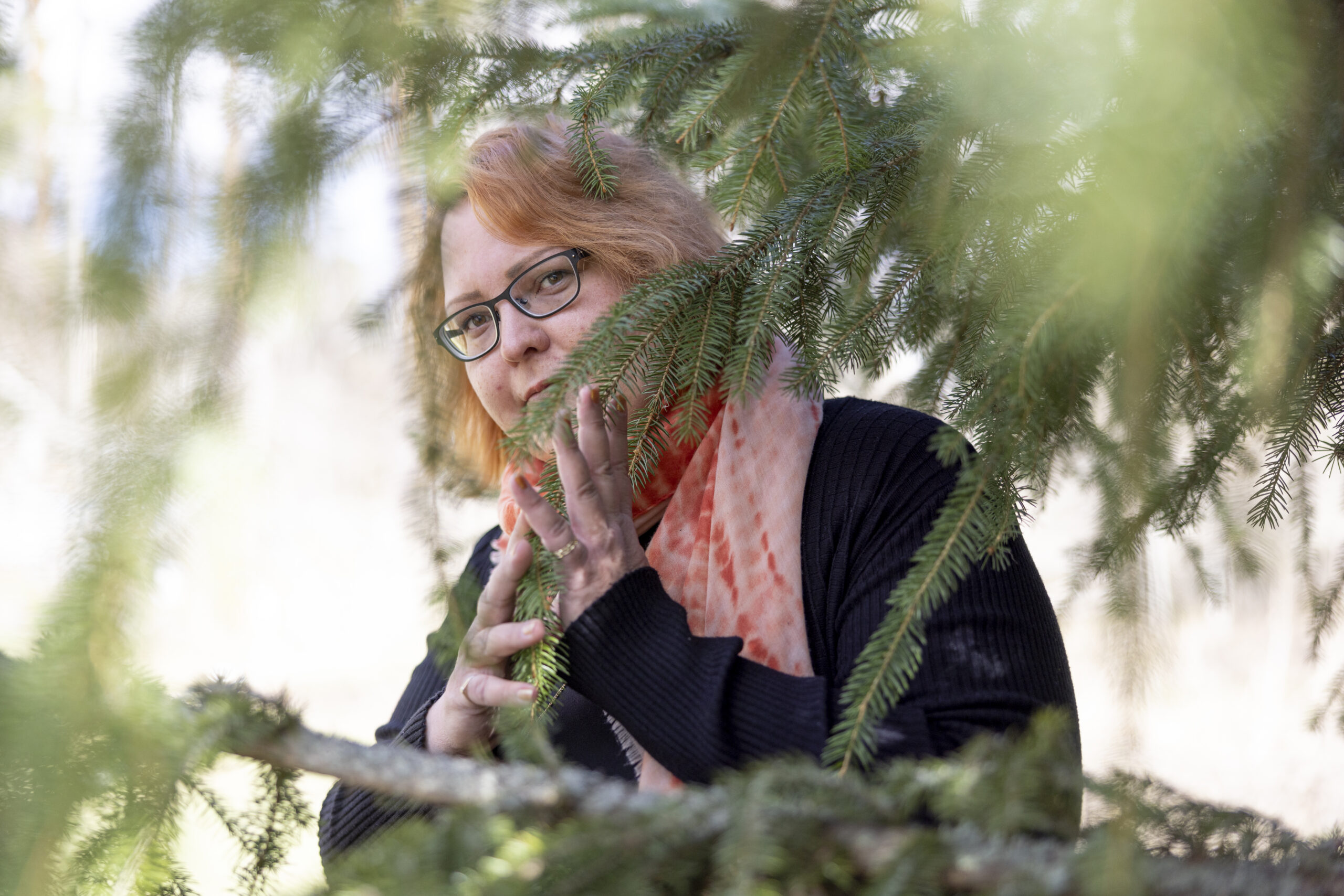 Runoilija Aurora Tinja Eronen kurkistaa puiden siimeksestä