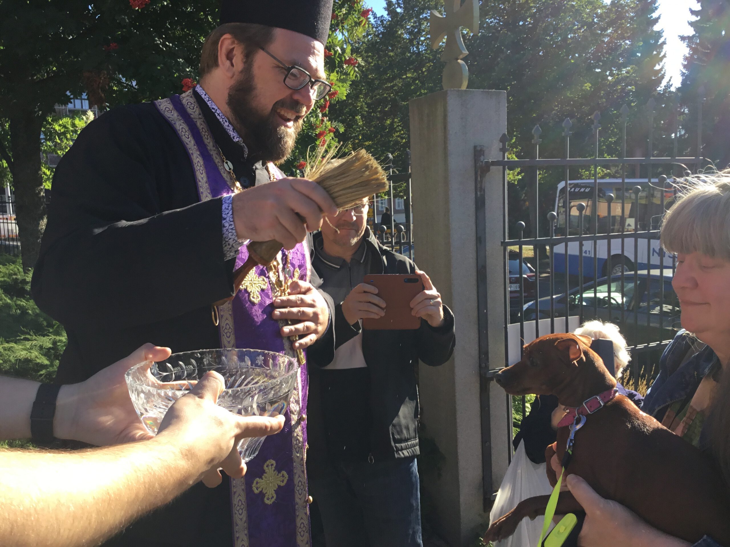 Isä Aleksej Sjöberg vihmoo koiraa luomakunnan päivänä pyhitetyllä vedellä