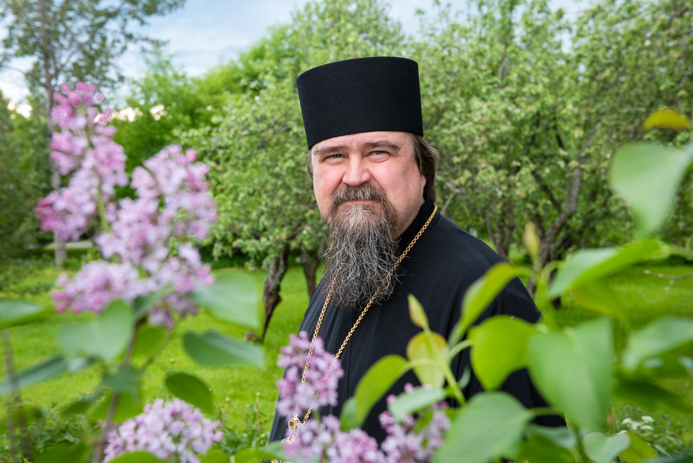 Haminan piispa Sergei kuvattuna kukkien keskellä Valamon luostarin puutarhassa