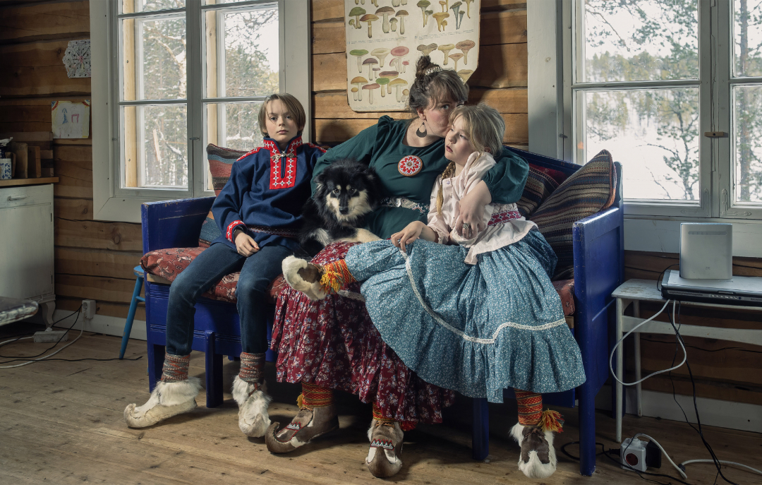 Koltansaamelainen perhe istuu sohvalla kotonaan